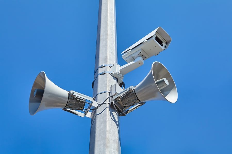 A surveillance camera and horn speakers installed on a pole.