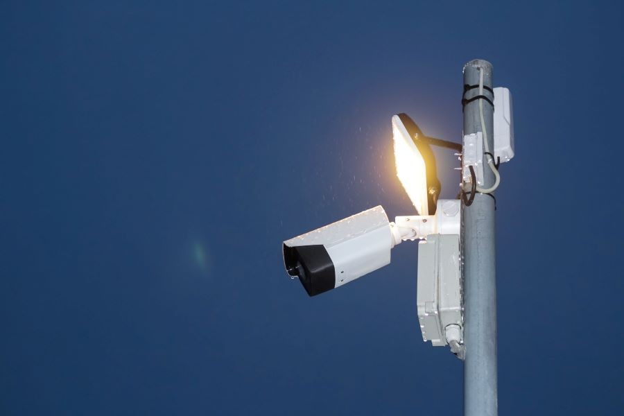 A security camera and a light on a pole.