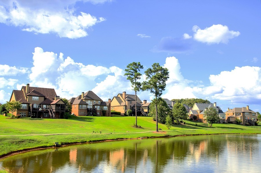 A row of houses in a suburban neighborhood backing to a small lake.  