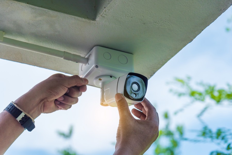 a person wearing a watch installing a security camera in place