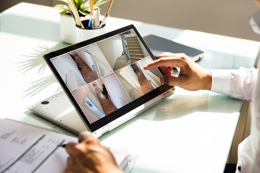 man at desk looking at tablet with photos of different areas of a building