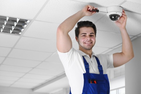 A professional installer working on a ceiling mounted smart camera.