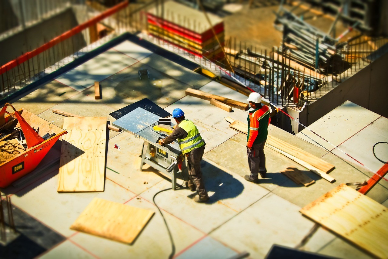 Two workers preparing wood boards at a construction site. 